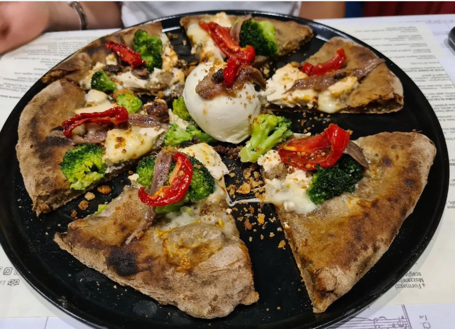 Spicchi di pizza gourmet con burrata al centro del piatto. Ottima pizza gourmet di Le Quinte a Catania.