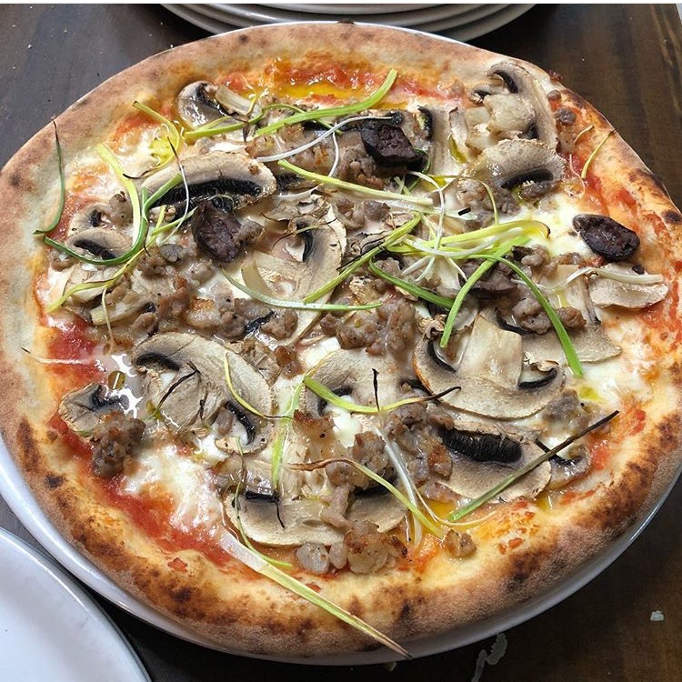 Deliziosa vista da vicino di una pizza con funghi, salsiccia.